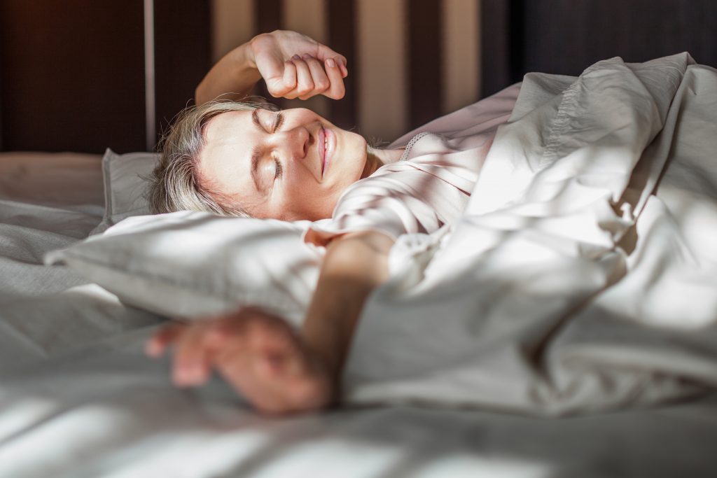 Frau räkelt sich nach dem Erwachen am Morgen im Bett