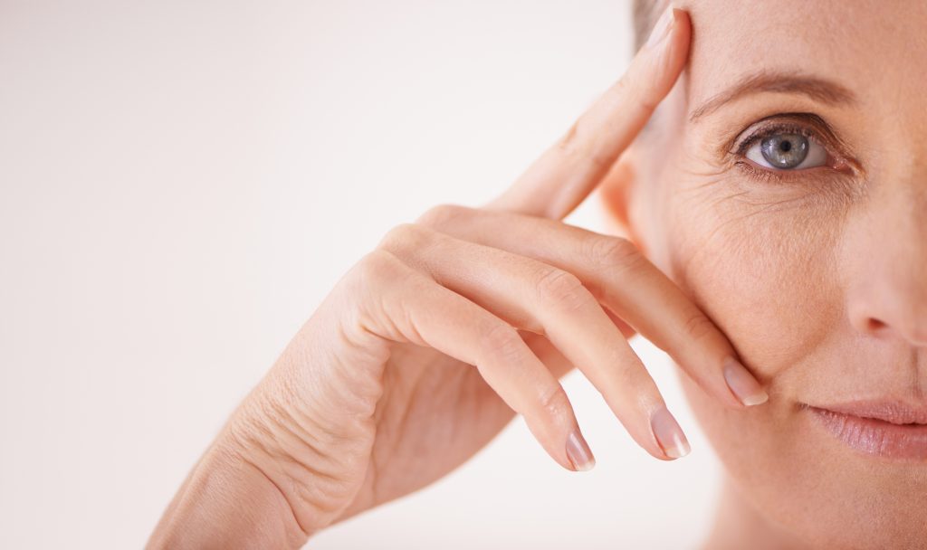 Porträt einer Frau, das Gesicht halb angeschnitten, die sich mit der Hand ins Gesicht fasst