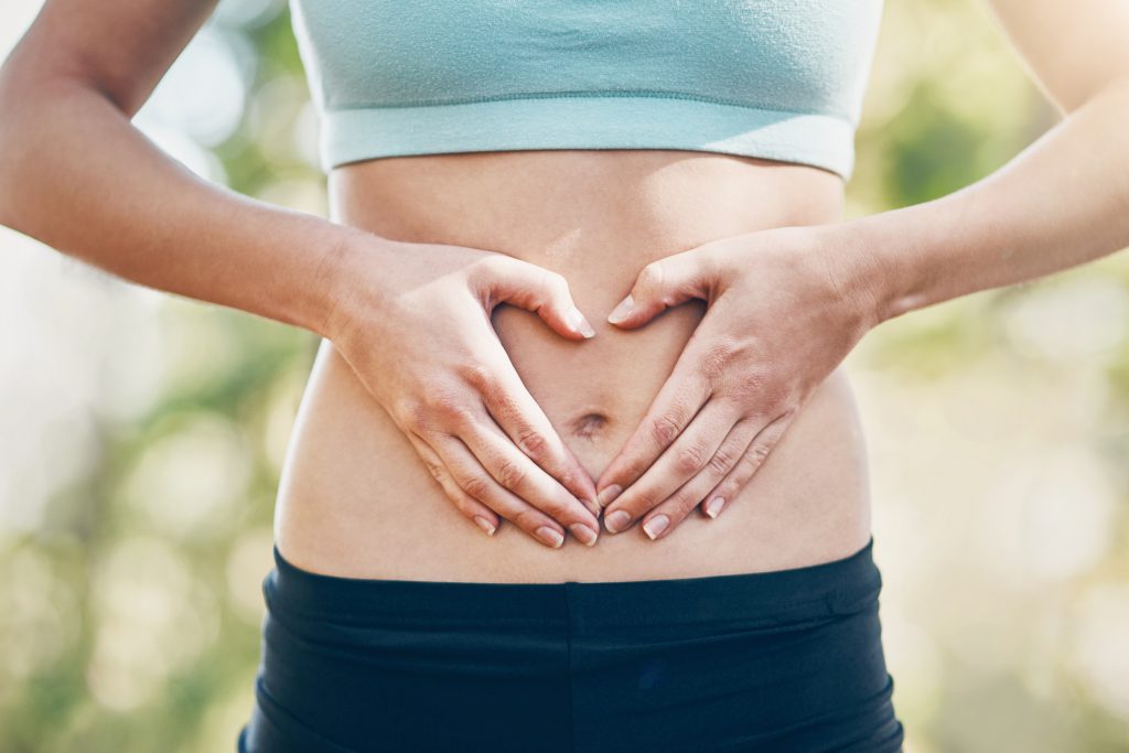 Eine Frau formt mit den Händen ein Herz vor ihrem Bauch